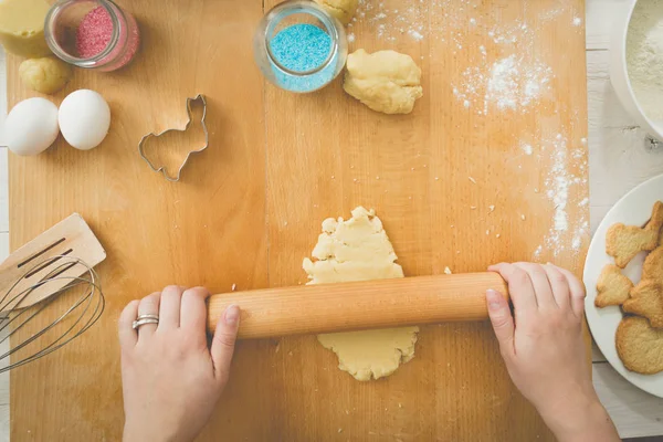 Молодая женщина катит тесто на деревянной доске — стоковое фото