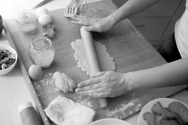 Black and white image of woman using rolling pin while cooking