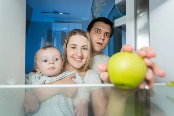 View from inside the refrigerator on smiling family looking for