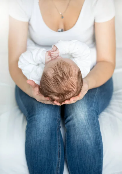 Primer plano de la joven madre cariñosa sosteniendo la cabeza de su pequeño bebé — Foto de Stock