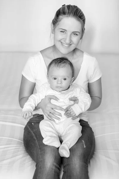 Черно-белый портрет молодой улыбающейся матери, сидящей с ним — стоковое фото