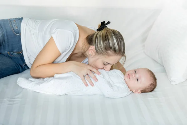 Smiling mother playing on bed with her cute baby boy — Stock Photo, Image