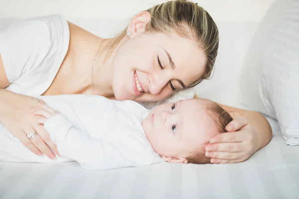 Retrato de una madre sonriente acostada con un bebé de 3 meses en la cama — Foto de Stock