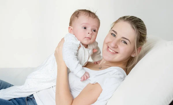 Portrait of beautiful smiling woman lying with her cute baby on — Stock Photo, Image