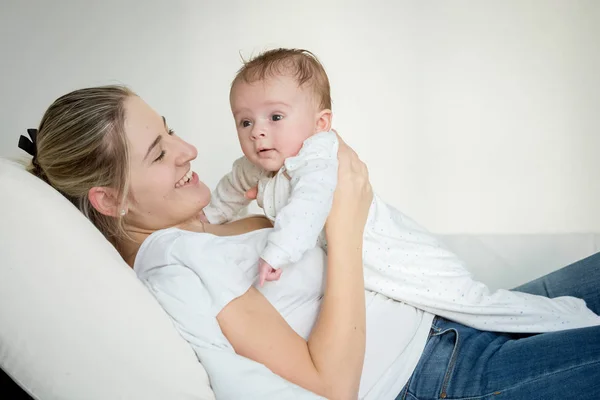 Portrait of cheerful young mother lying with her baby on bed — Stock Photo, Image