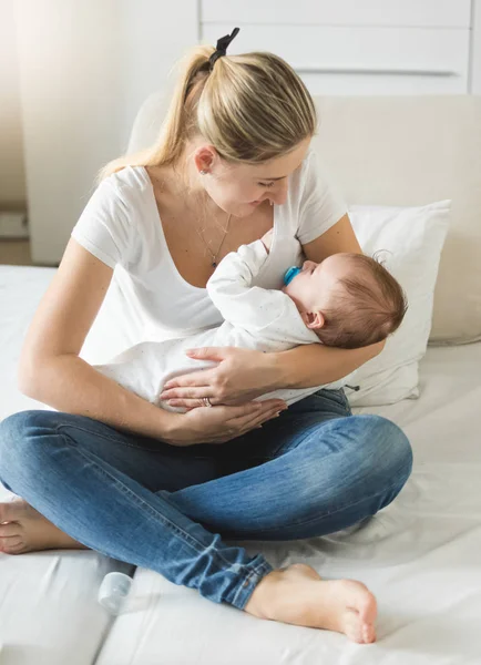 3 aylık bebek oğlu ile yatağın üstüne oturan genç anne — Stok fotoğraf