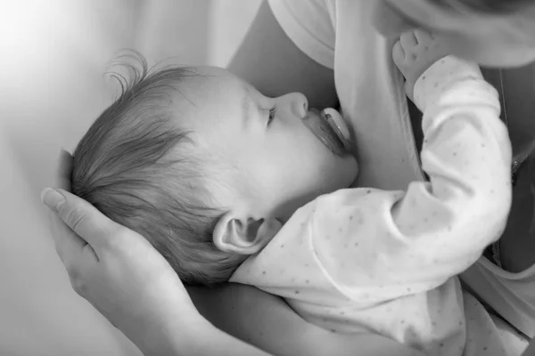Image noir et blanc de mignon bébé garçon dormant sur les mains des mères — Photo