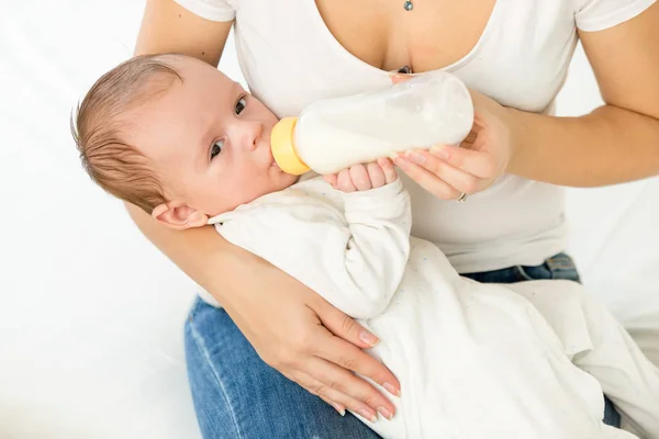 Retrato de madre joven sosteniendo a su bebé y alimentándose con leche —  Fotos de Stock
