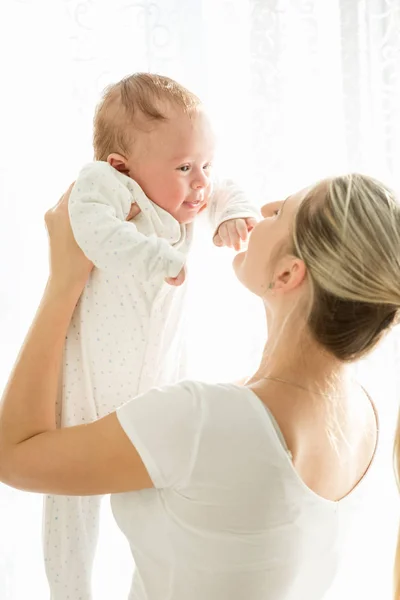 แม่สาวที่มีความสุข จับลูกอายุ 3 เดือนไว้ที่หน้าต่าง — ภาพถ่ายสต็อก