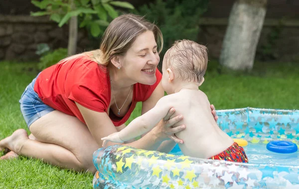 Happy young mother playing with her baby swimming in pool — Stock Photo, Image