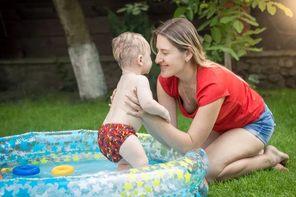 Młoda matka przytulanie jej synka w basenie w ogrodzie — Zdjęcie stockowe