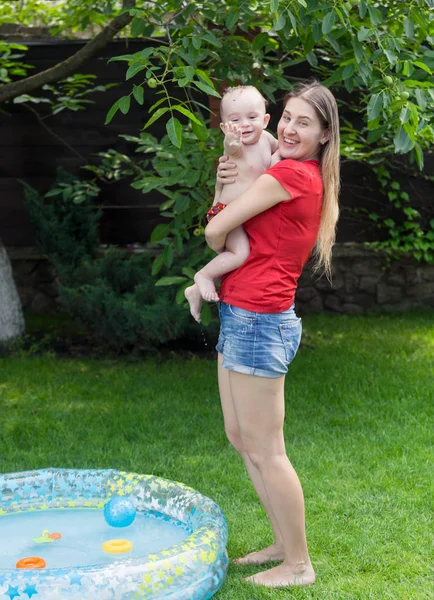 Vrolijke moeder haar babyjongen omarmen na het zwemmen in zwembad — Stockfoto