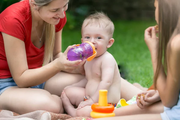 Lindo bebé bebiendo jugo de biberón en el picnic en el parque —  Fotos de Stock