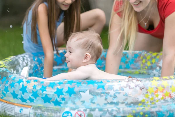 Bonito menino nadando na piscina ao ar livre com mãe e irmã — Fotografia de Stock