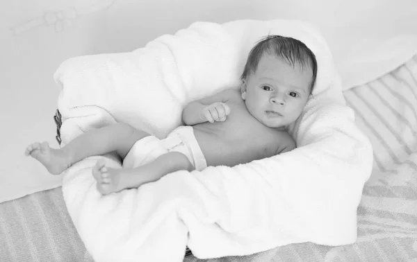 Monochromes Foto des niedlichen Jungen, der auf einem großen Kissen liegt — Stockfoto