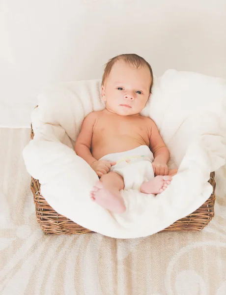 Niedlicher kleiner Junge liegt in großem Korb auf Decke — Stockfoto