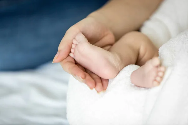 Imagen de primer plano de la madre sosteniendo los pies del bebé recién nacido en la cama — Foto de Stock