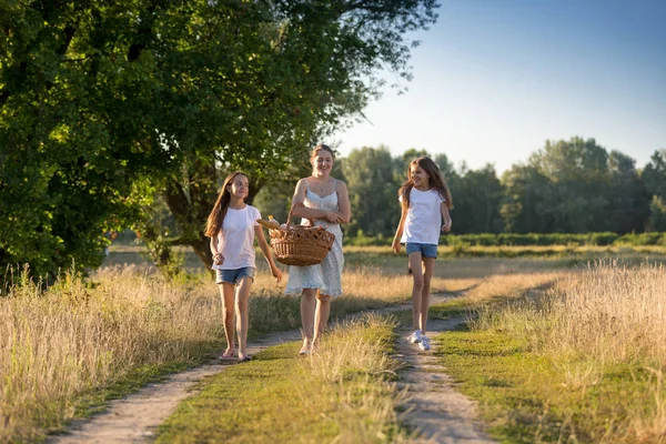 Meninas felizes andando com a mãe na estrada rural — Fotografia de Stock