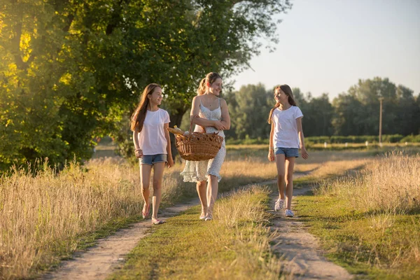 Young mother walking to picnic with her two daughter — Stock Photo, Image