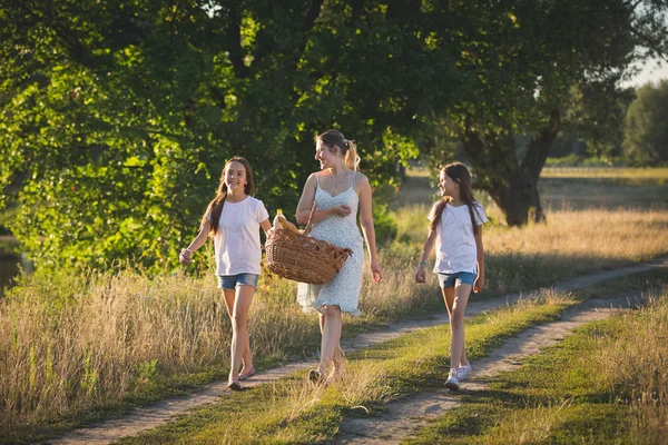 Портрет счастливой матери с двумя дочерьми, идущими вдоль реки — стоковое фото