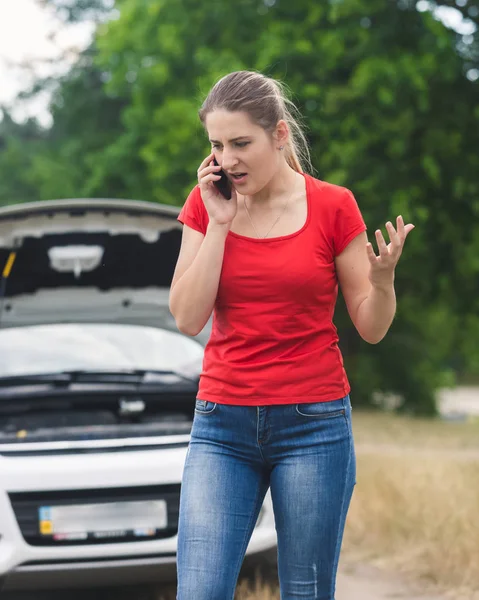 Angry young woman shouting in mobile phone because of the broken Stock Picture