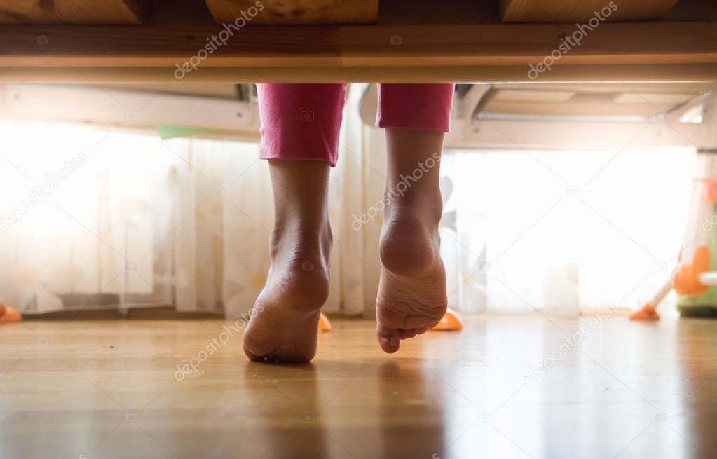 Girls feet under bed at sunny morning