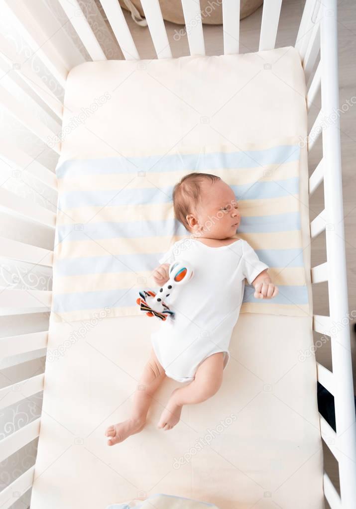 Little baby lying in white cradle at sunny day