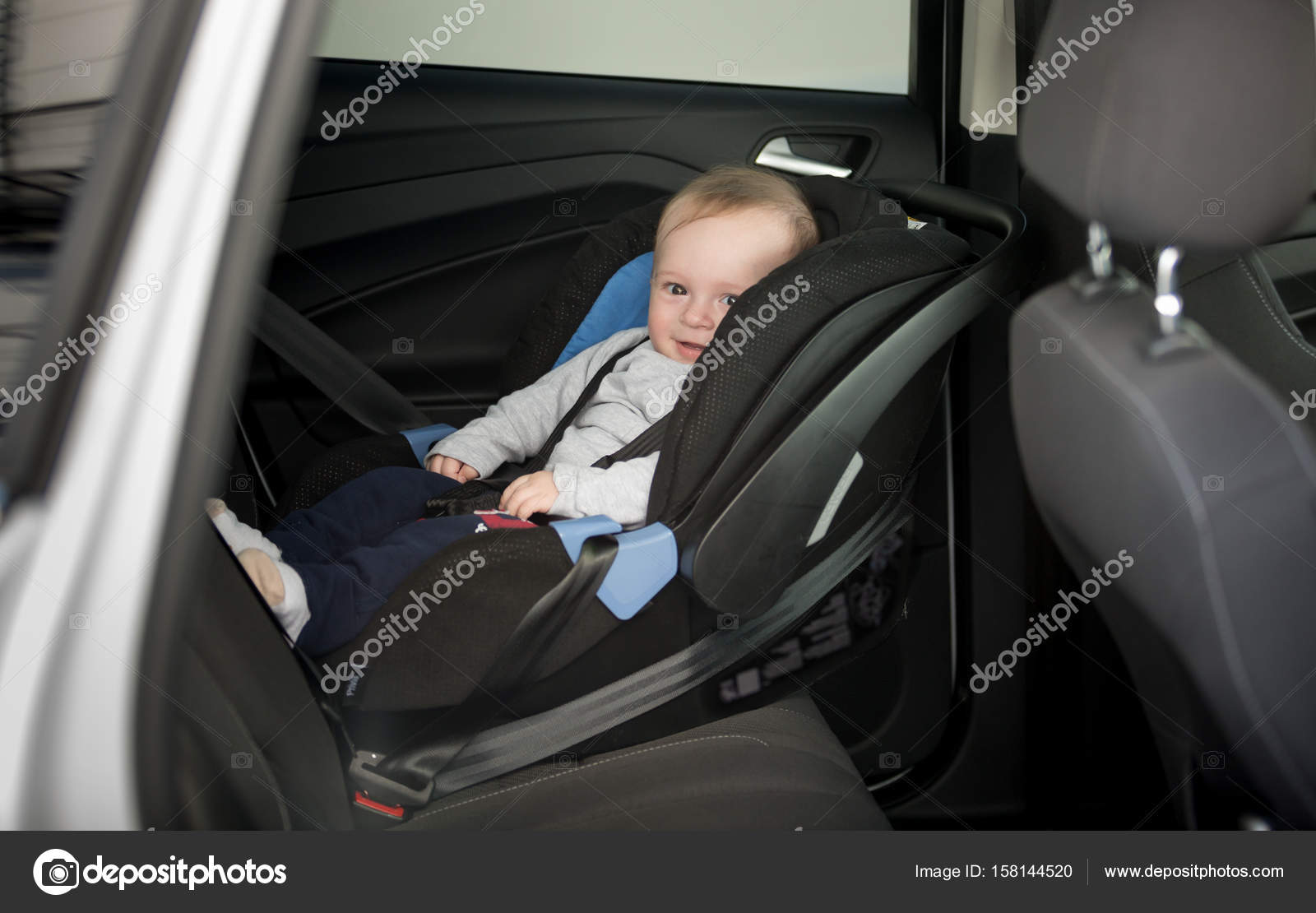 6 Months Old Baby Boy Sitting In Child Seat At Car Stock