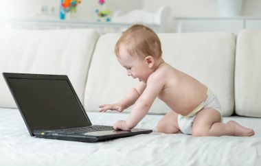 Bebeğim yatağa sürünerek ve ilgi ile laptop arıyorum