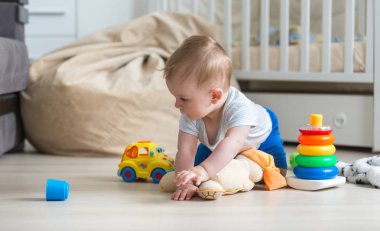 Yerde sürünen ve oyuncak araba ile oynayan sevimli bebek çocuk