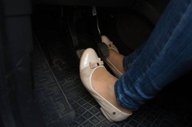 Closeup of female driver feet on car pedals clipart