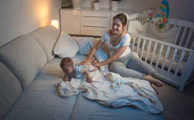 Geceleri yatakta oturuyor ve adora tutan güzel genç anne