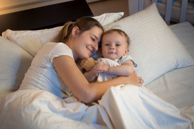 Geceleri yatakta yatan ve onun ba sarılma gülümseyen güzel kadın