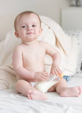 Güzel şirin bebek bezli süt şişesi ile oturan