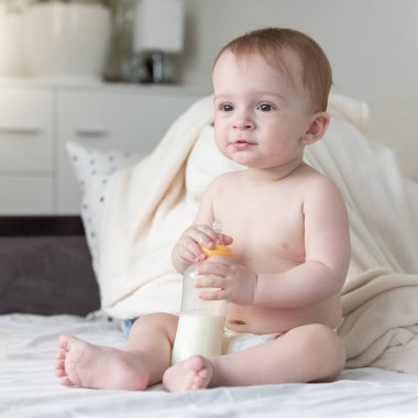 Güzel bebek çocuk yatağa oturmuş ve onun bot tutan bezli