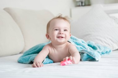 Yatakta mavi havlu altında yalan ve plastik tutarak bebek 