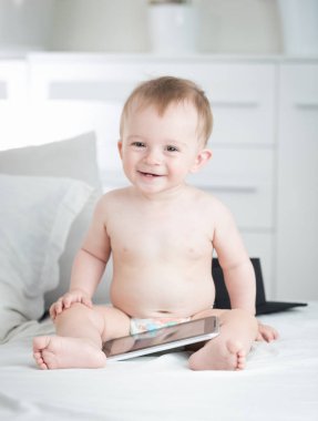Tablet pc ile birlikte oturan mezuniyet şapkalı erkek mutlu gülen bebek