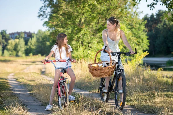 Chica feliz montando en bicicleta con su madre en el prado — Foto de Stock