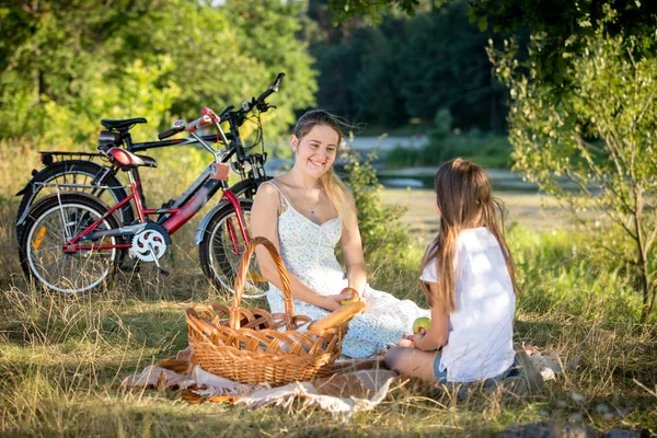 10 let stará dívka s piknik u řeky s mladou matkou — Stock fotografie