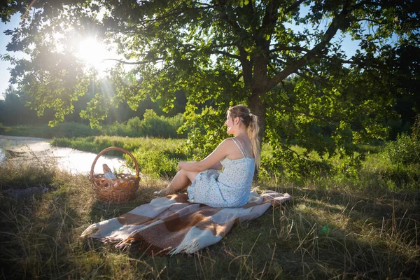 Hermosa mujer relajándose en la manta bajo el árbol y mirando su — Foto de Stock
