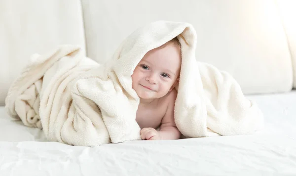 Adorable bébé garçon assis sur le lit et couvrant de couverture — Photo