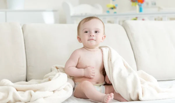 Adorable bébé garçon assis sur le lit et couvrant de couverture — Photo