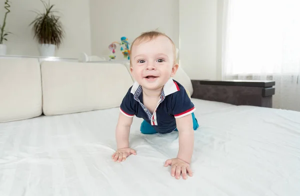 Cute usmívající se dítě lezou na postel a při pohledu na fotoaparát — Stock fotografie