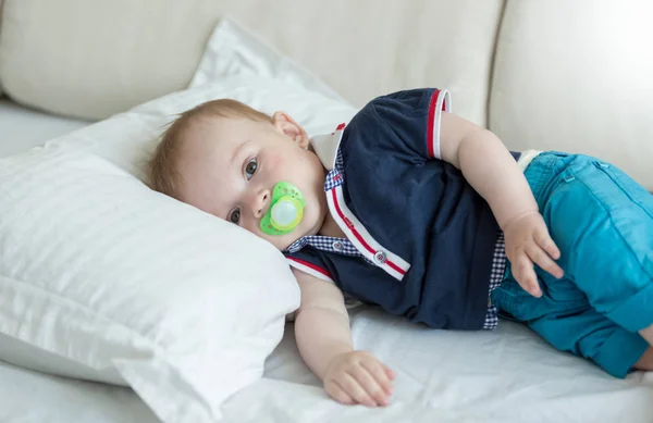 Portrait de mignon bébé garçon avec sucette couché sur le lit — Photo