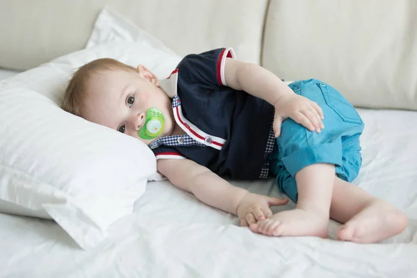 Bébé garçon avec sucette couché sur l'oreiller sur le canapé — Photo