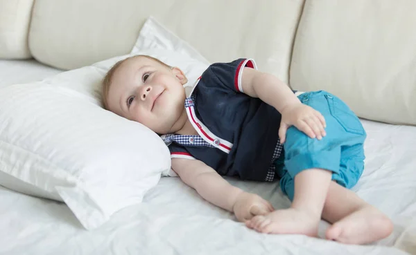 Дитячий хлопчик лежить на великій подушці на ліжку — стокове фото