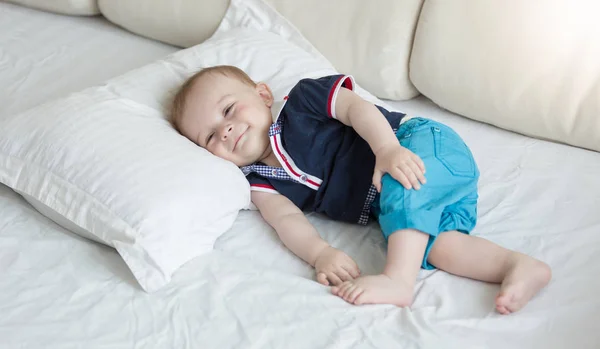 1 year old baby lying on big pillow on bed