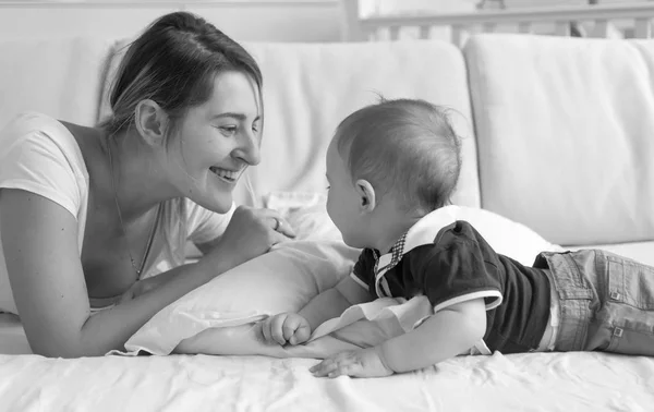 男の子の赤ちゃんと横たわっている陽気な若い母親の白黒の肖像画 — ストック写真