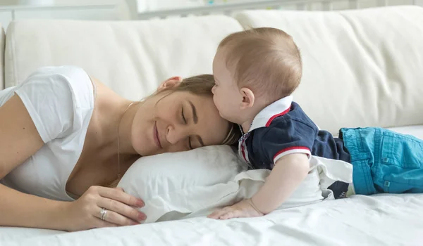 Portrait of cute baby boy lying with young mother on bed — Stock Photo, Image