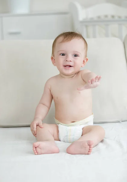 기저귀 침대에 앉아 귀여운 웃는 아기 — 스톡 사진
